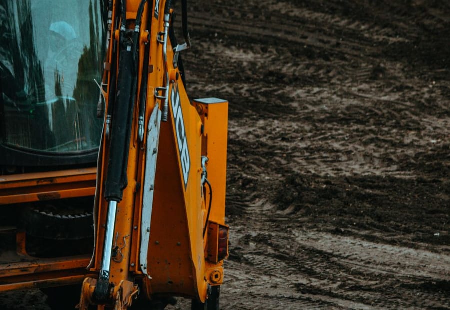 Excavator removing a failed drainfield to build a replacement mound on a rural Blue Earth County lot